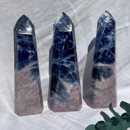 Three sodalite crystal obelisks with blue and pink marbled patterns on a white background.