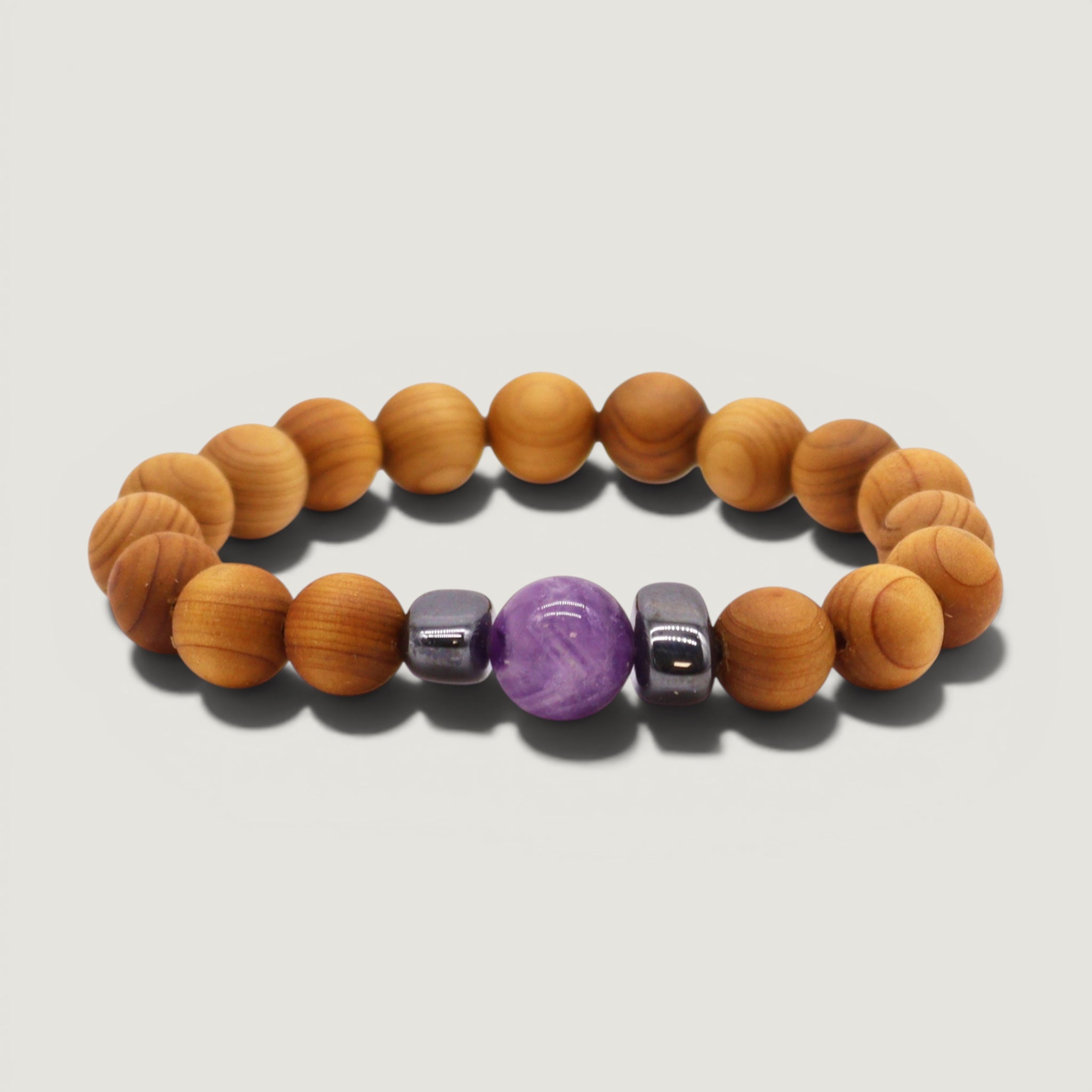 Cedar wood beaded bracelet with purple amethyst and metallic looking hematite beads on a light grey background