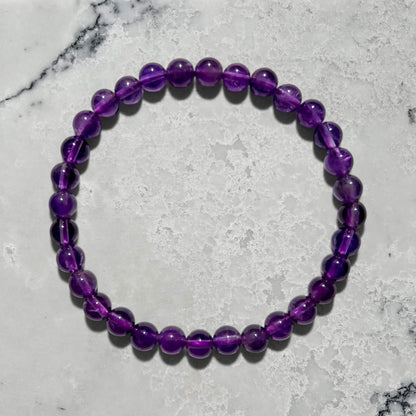 Purple Amethyst bead bracelet on a marble surface