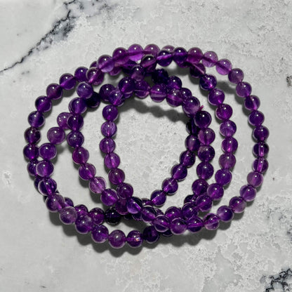 Stack of purple Amethyst bead bracelets on a marble surface