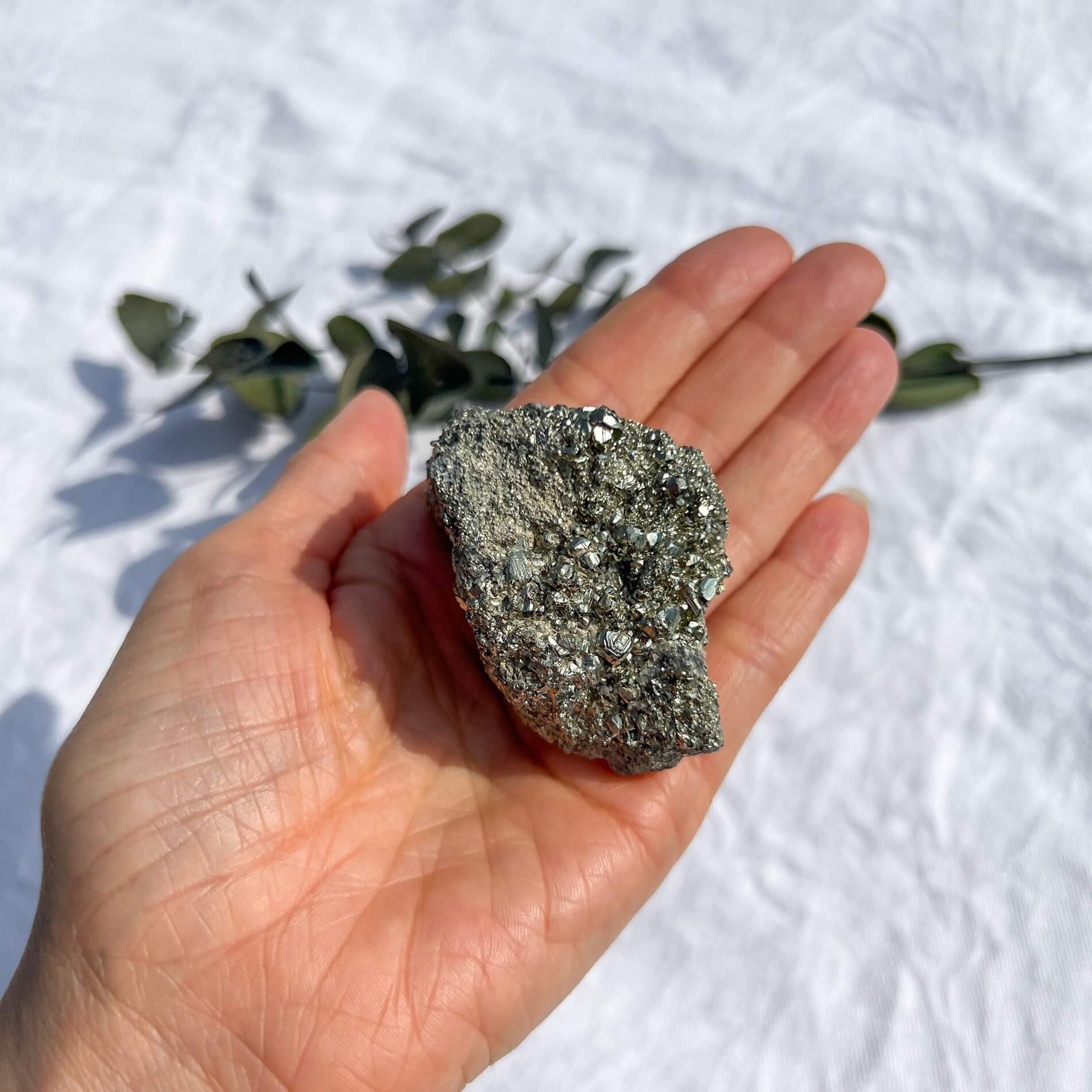 An extra large glimmering golden pyrite crystal cluster held in an outstretched hand