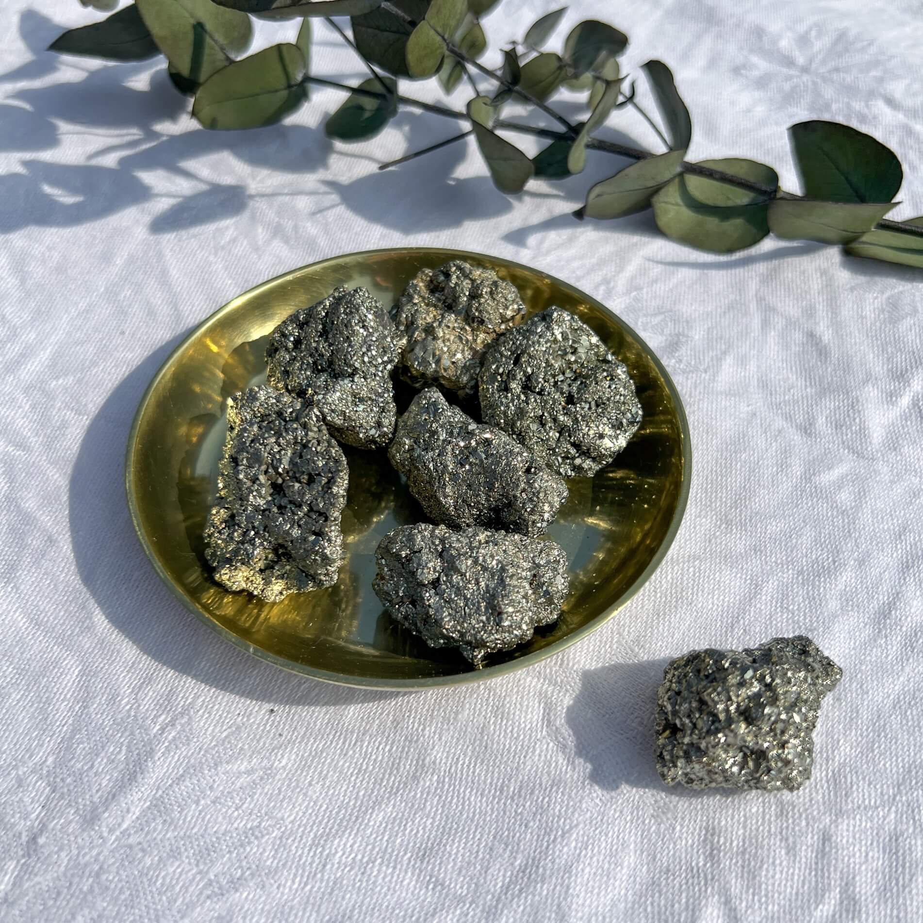 A small brass dish filled with small sparkling metallic golden pyrite crystal clusters