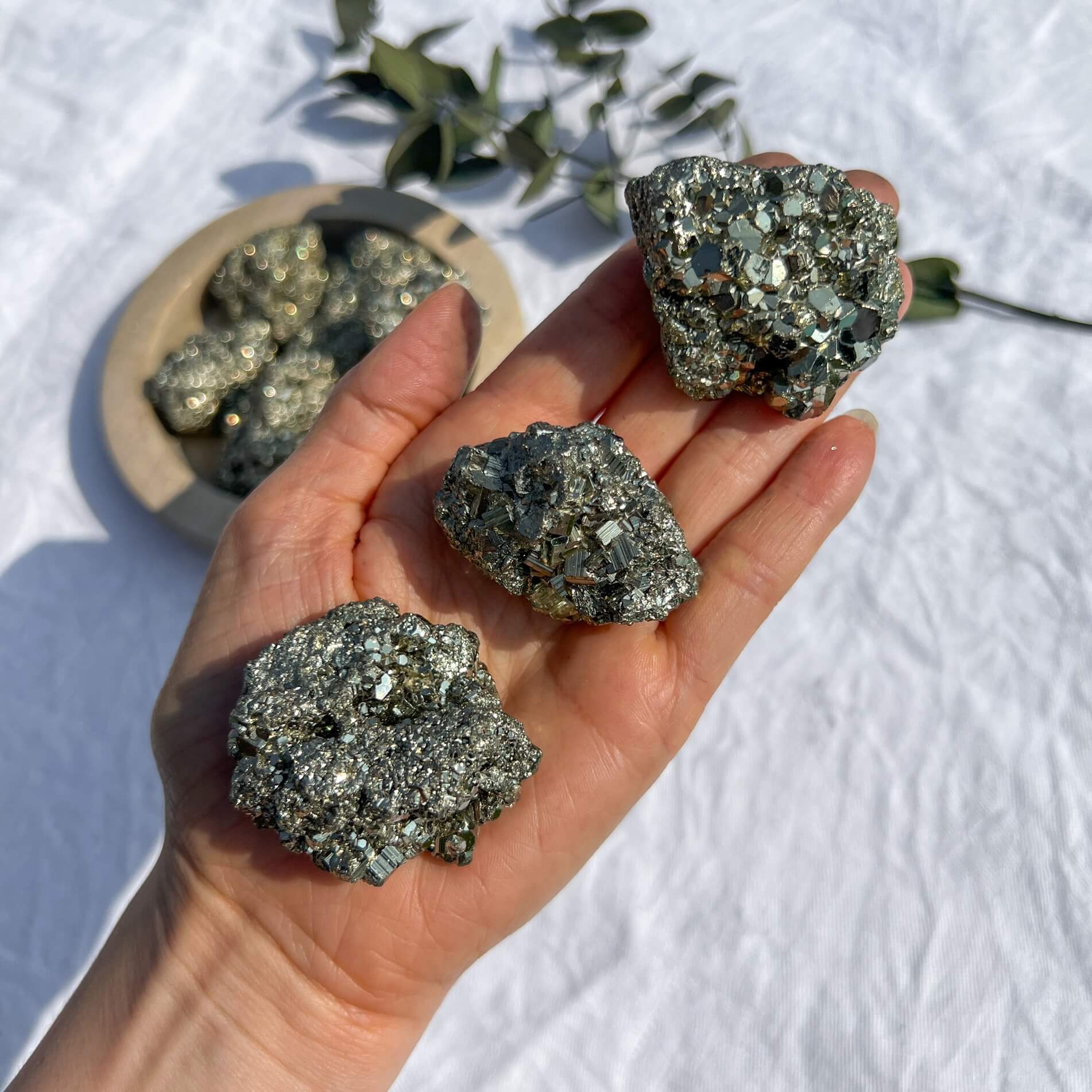 An outstretched hand with three impressive golden metallic pyrite crystal clusters