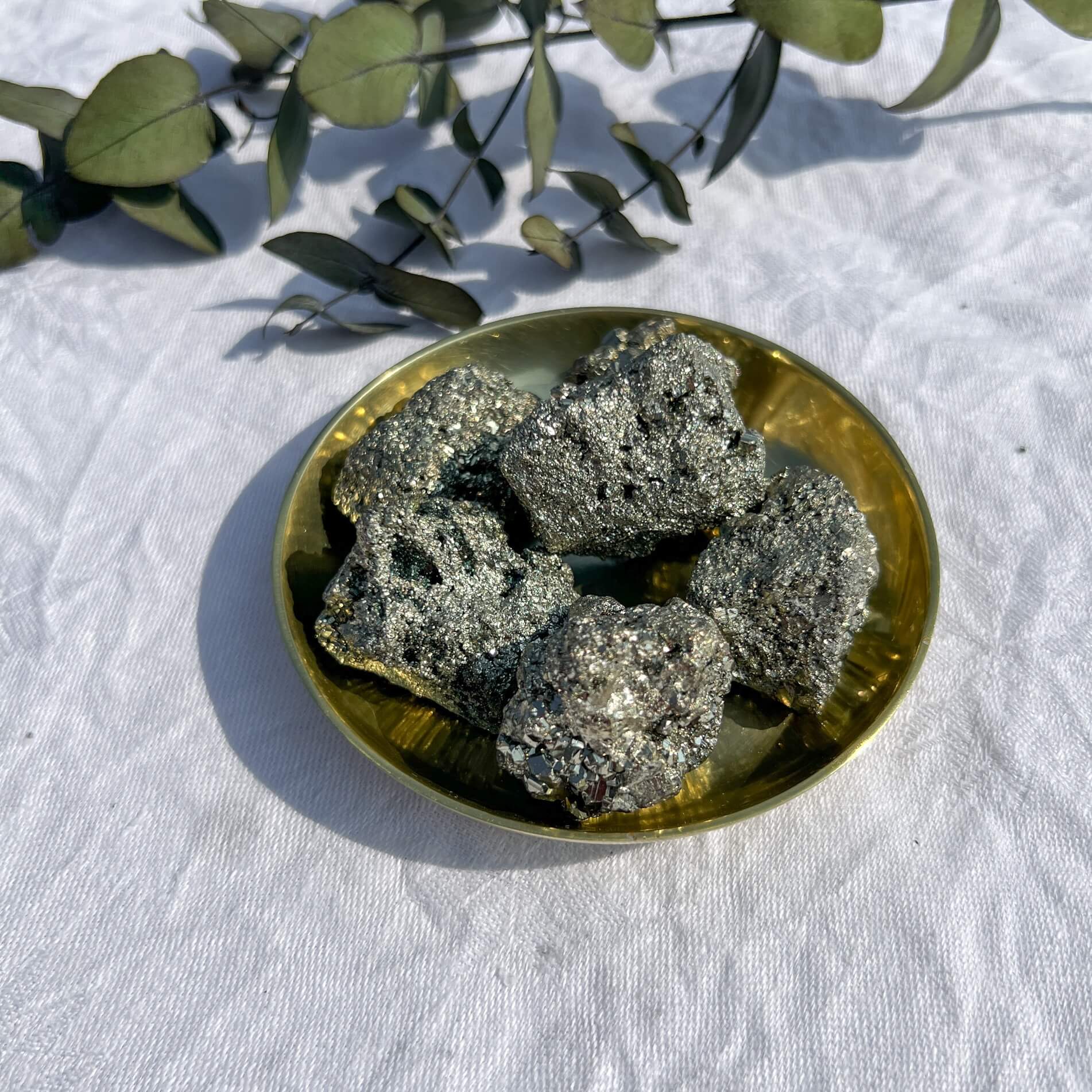 A small brass dish filled sparkly golden pyrite crystal clusters