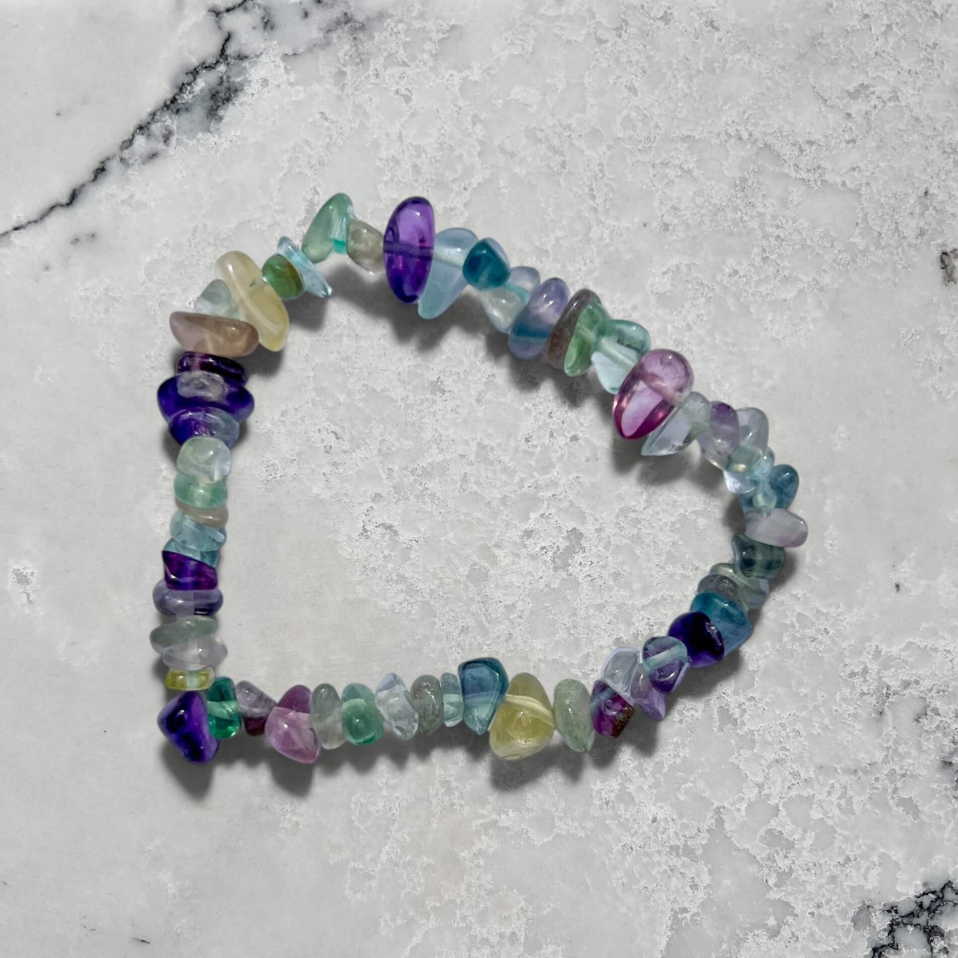 Multicolored rainbow fluorite gemstone chip bracelet on a marble surface