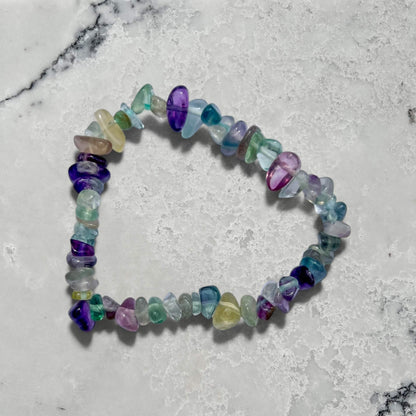 Multicolored rainbow fluorite gemstone chip bracelet on a marble surface