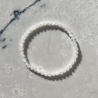 white moonstone crystal bead bracelet with subtle blue flashes on a white marble surface