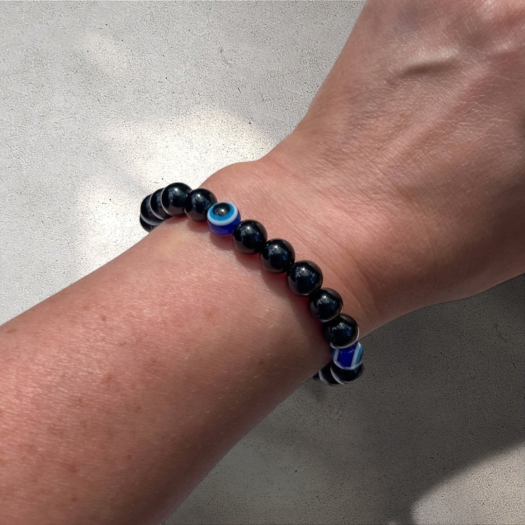 Rock + Realm Crystals black obsidian beaded bracelet with blue and white evil eye charms for protection and good luck worn on a woman's wrist