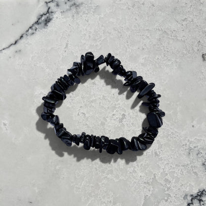 Rock + Realm Crystals black shungite chip bracelet with irregular stone pieces against a natural grey and white marble surface