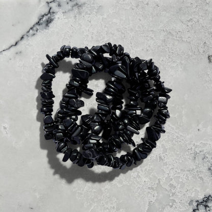 Stack of 4 Rock + Realm Crystals black shungite chip bracelets against a natural grey and white marble surface
