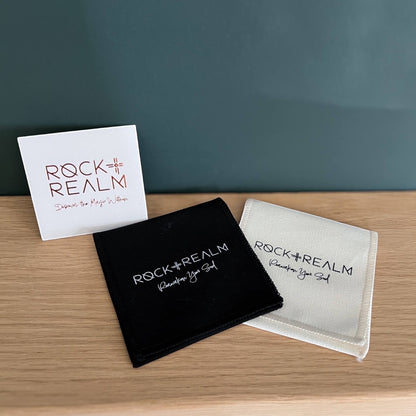 Rock + Realm Crystals branded black and white pouches with a white card. The card has a rose gold logo and text.