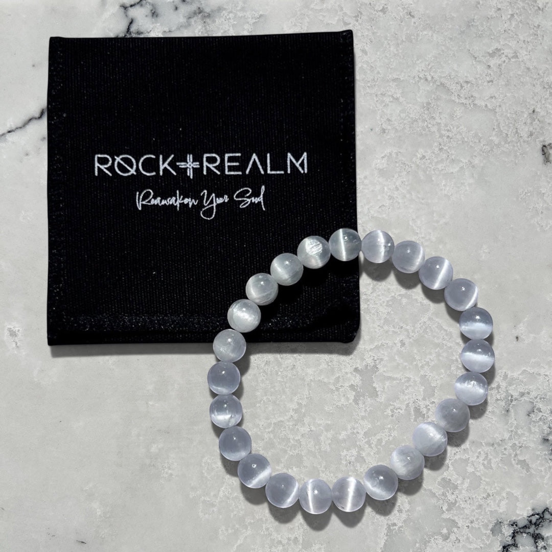 Rock + Realm large selenite crystal bead bracelet with a 'Rock + Realm' black branded jewellery pouch.