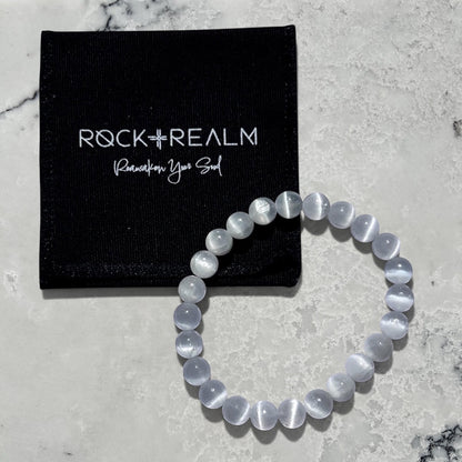 Rock + Realm large selenite crystal bead bracelet with a 'Rock + Realm' black branded jewellery pouch.