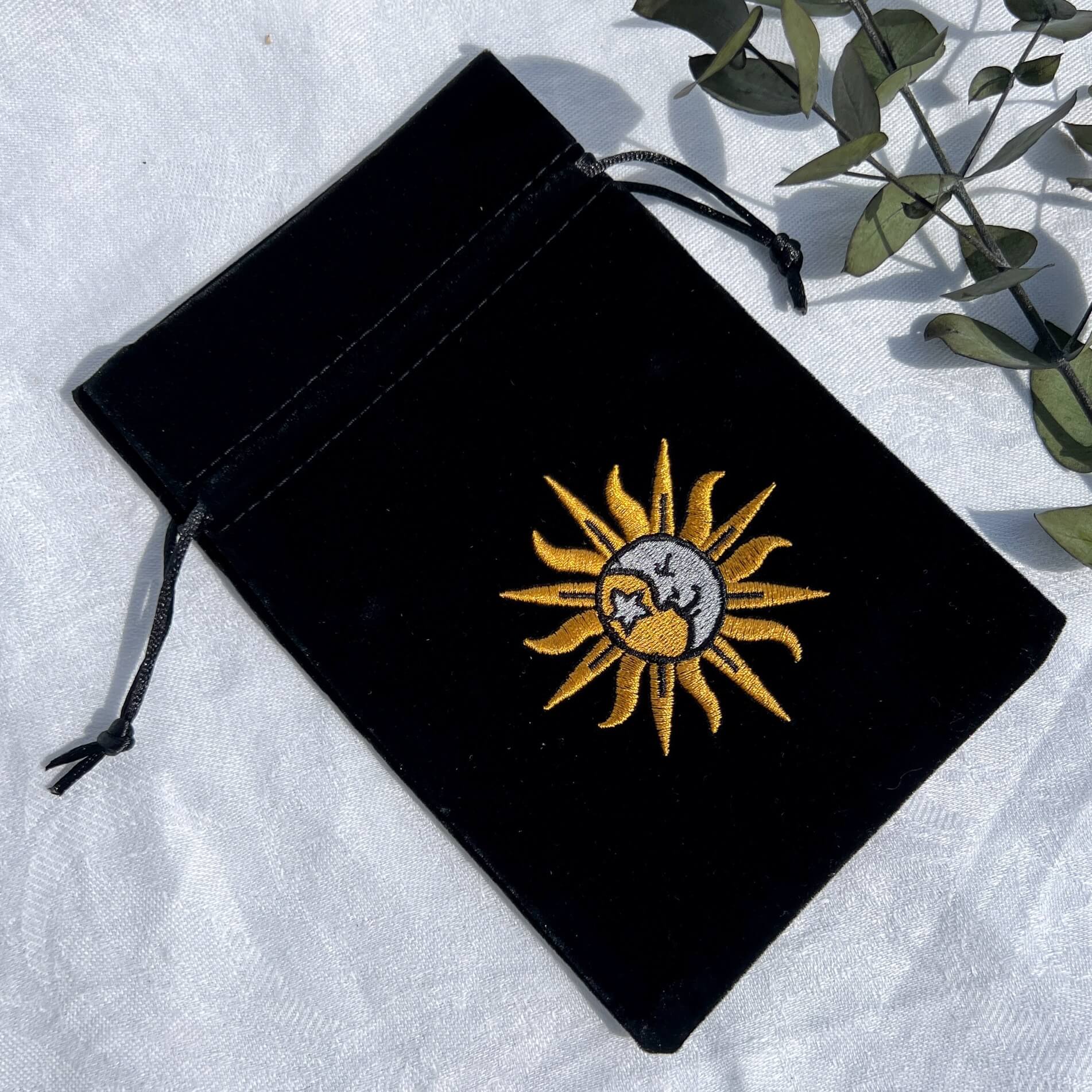 Black velvet celestial oracle card bag with an embroidered sun and moon emblem