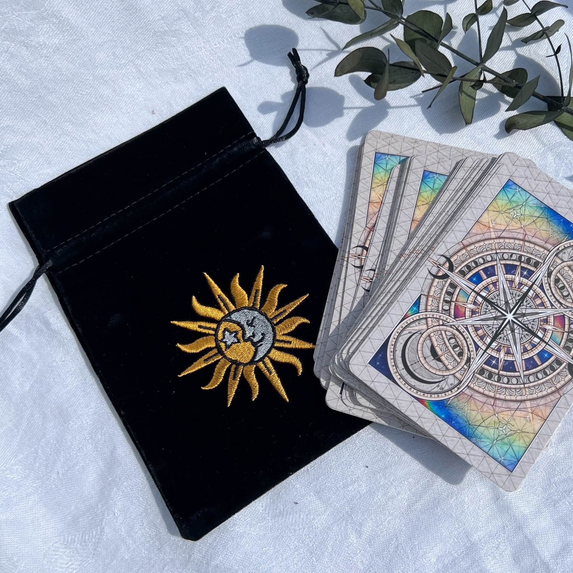Black velvet celestial oracle card bag with an embroidered sun and moon emblem and astro realms oracle deck