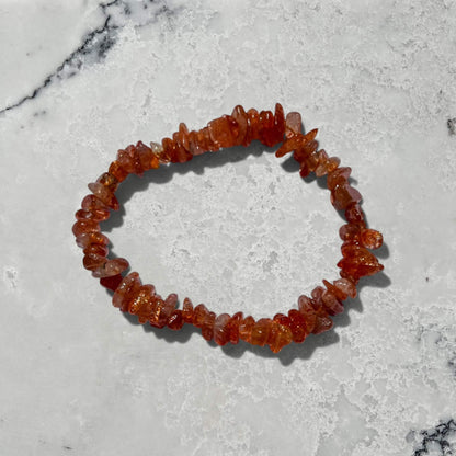 Orange high grade sunstone crystal chip bracelet with sparkle on a grey marble surface