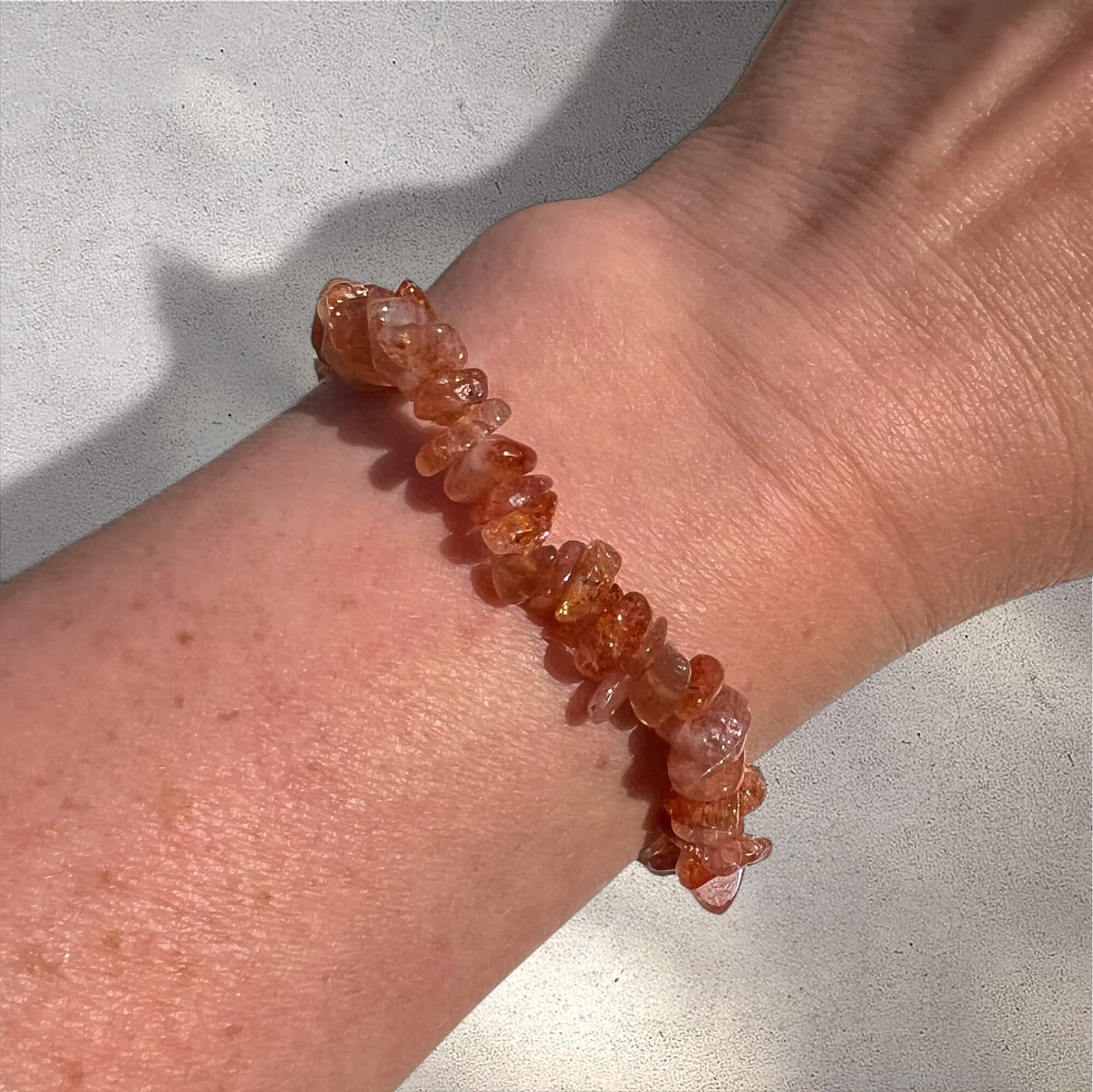 Close-up of a wrist wearing an Orange high grade sunstone crystal chip bracelet with sparkle