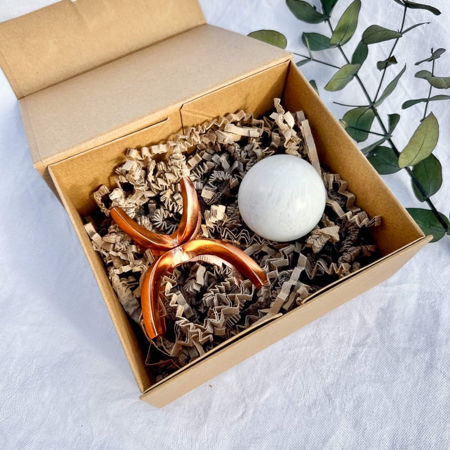 Kraft gift box with scolefcite sphere and rose gold sphere stand inside with crinkle cut filler