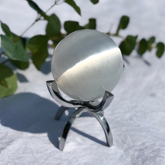 Extra large white and shiny selenite crystal sphere in an aluminium claw stand
