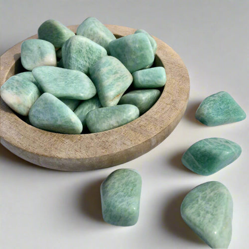 A shallow wooden dish filled with turquoise Amazonite tumble stones 