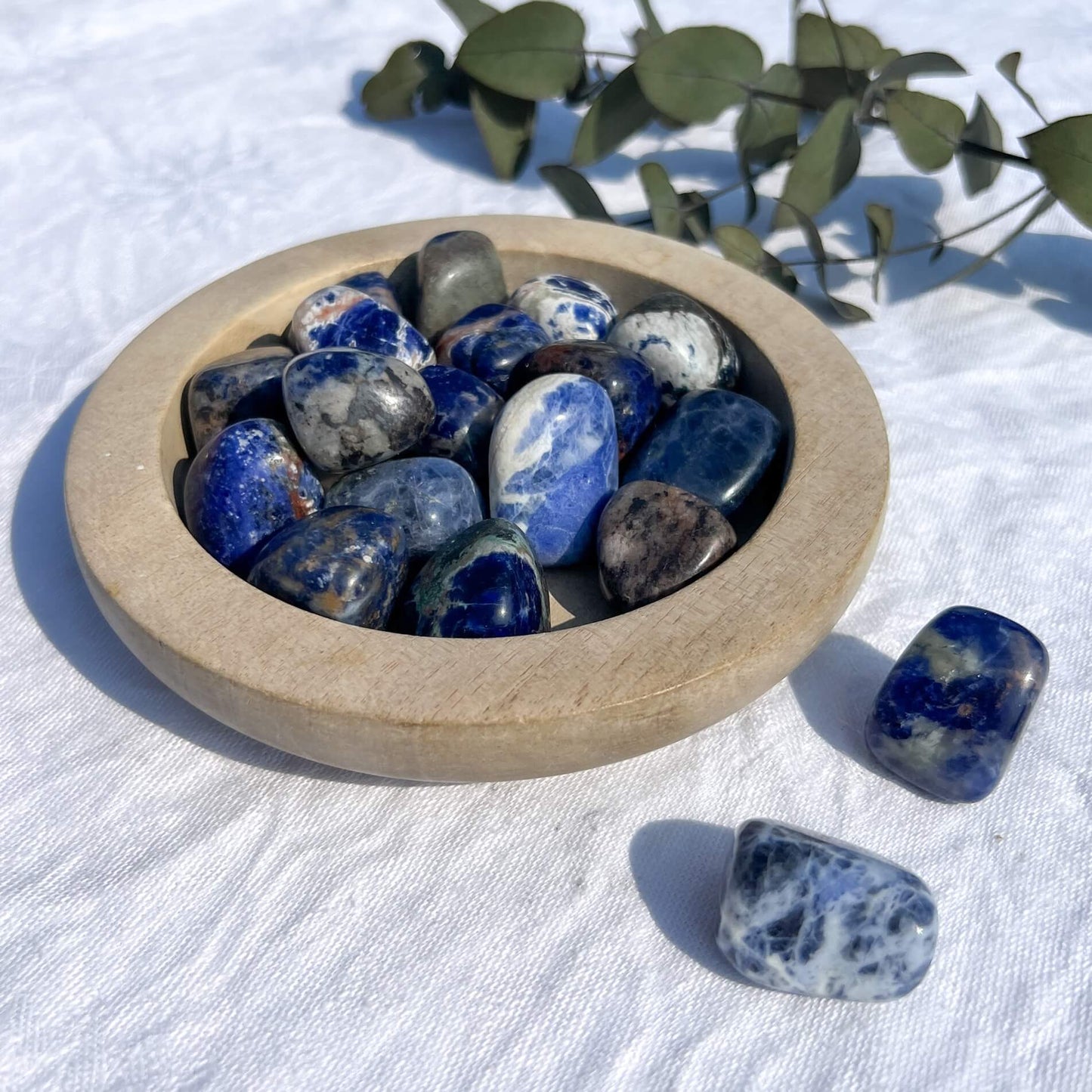 Wooden dish overflowing with extra large blue and white sodalite crystal tumblestones