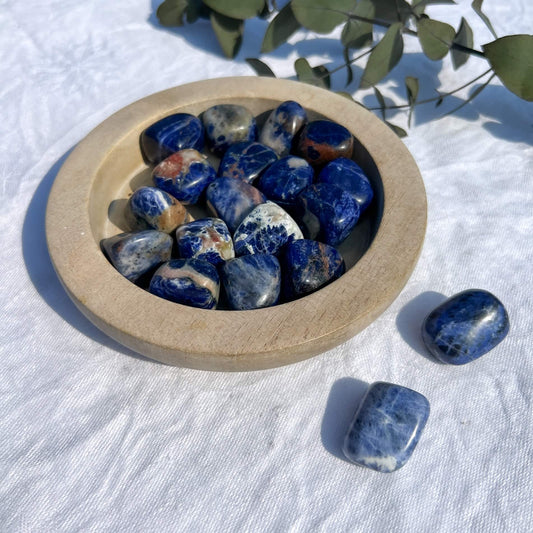 A wooden dish with blue and white large sodalite crystal tumblestones