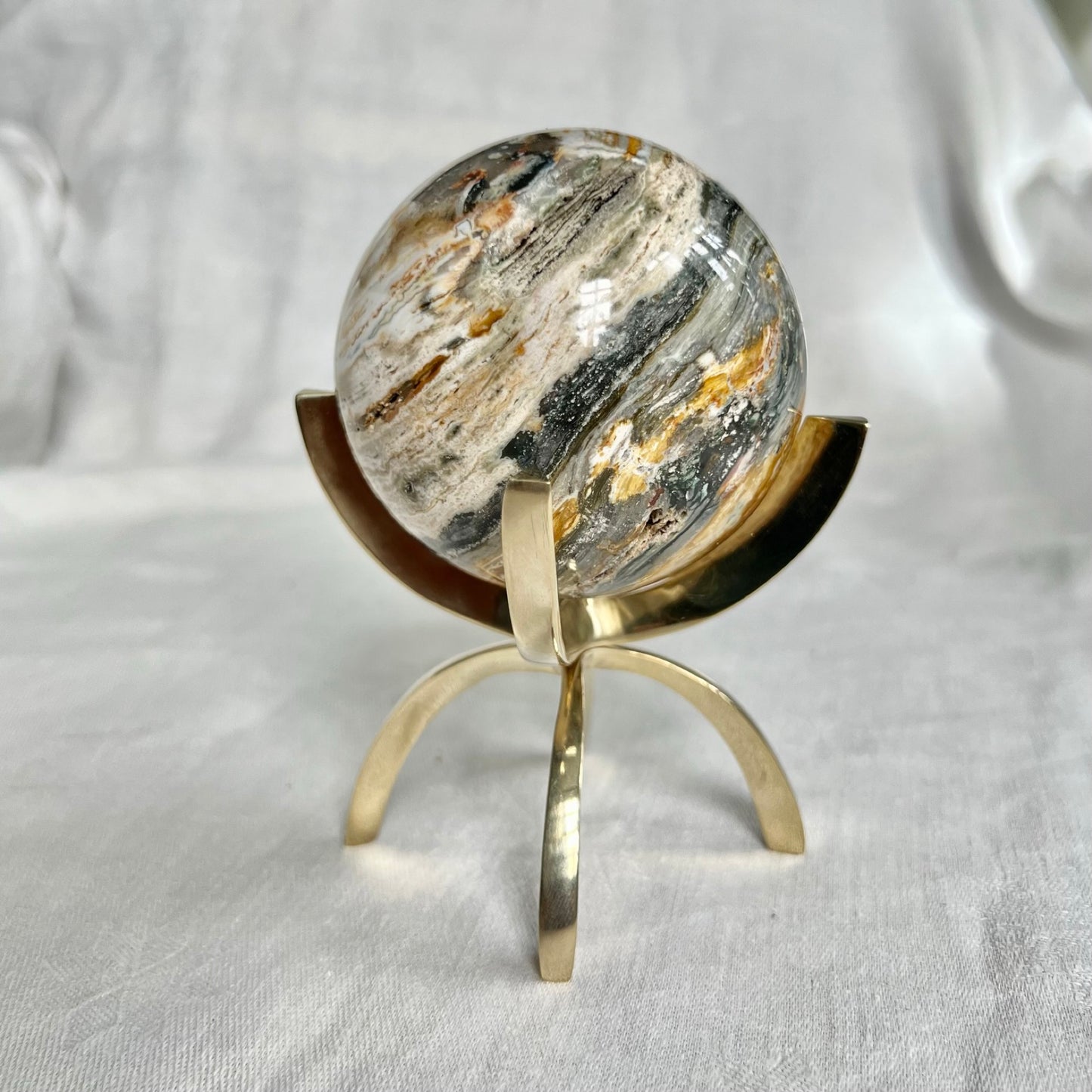 Grey, pink and cream ocean jasper crystal sphere in a large brass claw stand