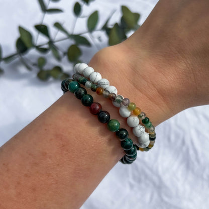 A woman's wrist wearing calming crystal bead bracelets in bloodstone, howlite & green jasper