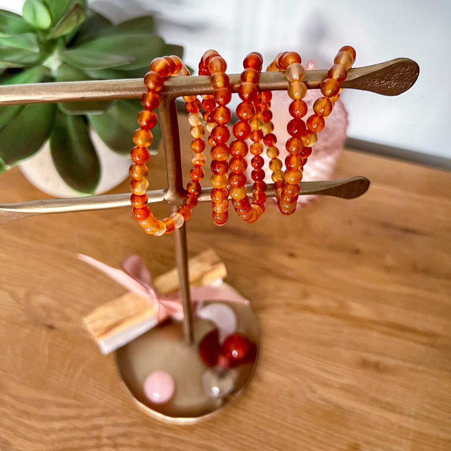 A brass jewellery stand hung vivid orange & red carnelian crystal bead bracelets