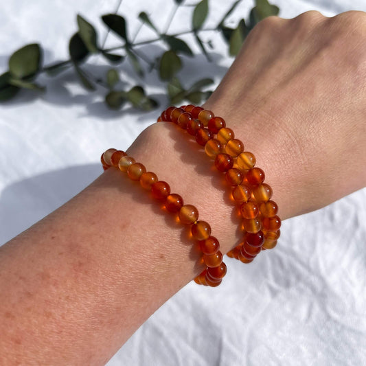 A lady's wrist with vivid orange & red carnelian crystal bead bracelets