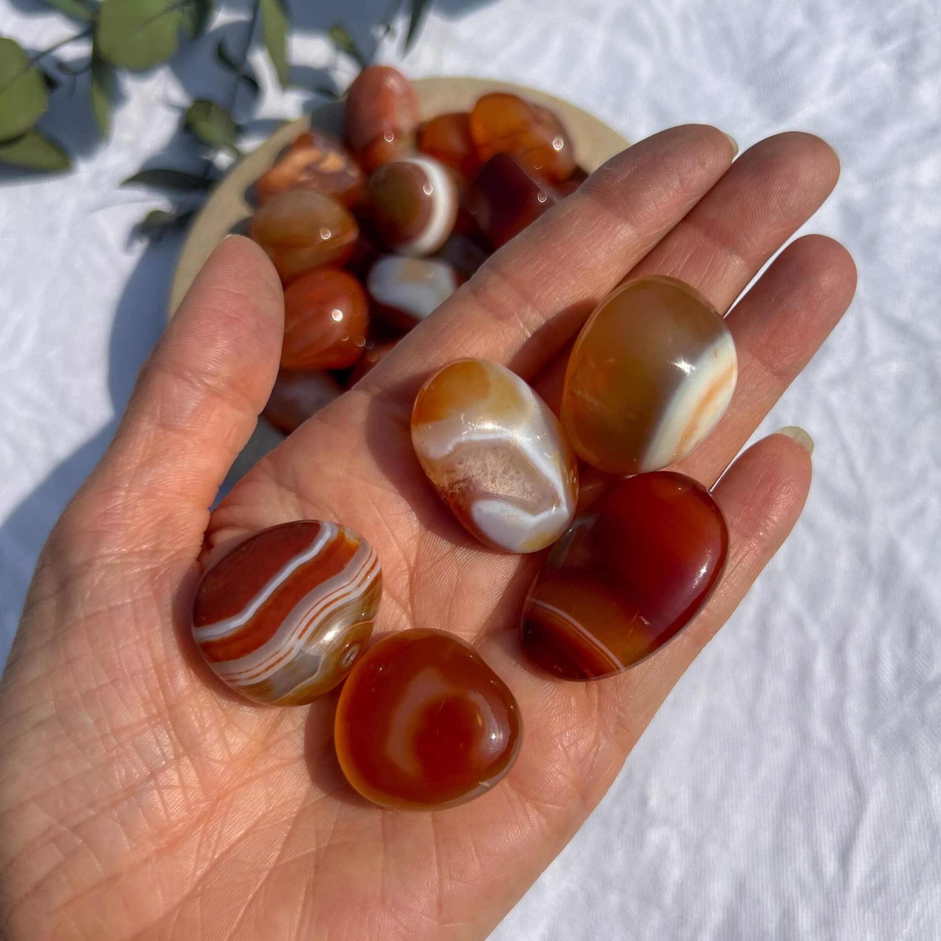 A handful of vibrant red and orange patterned carnelian crystal tumblestones