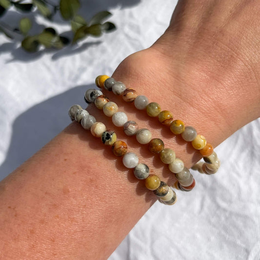 A lady's wrist sporting 3 yellow, white & amber coloured crazy lace agate crystal bead bracelets