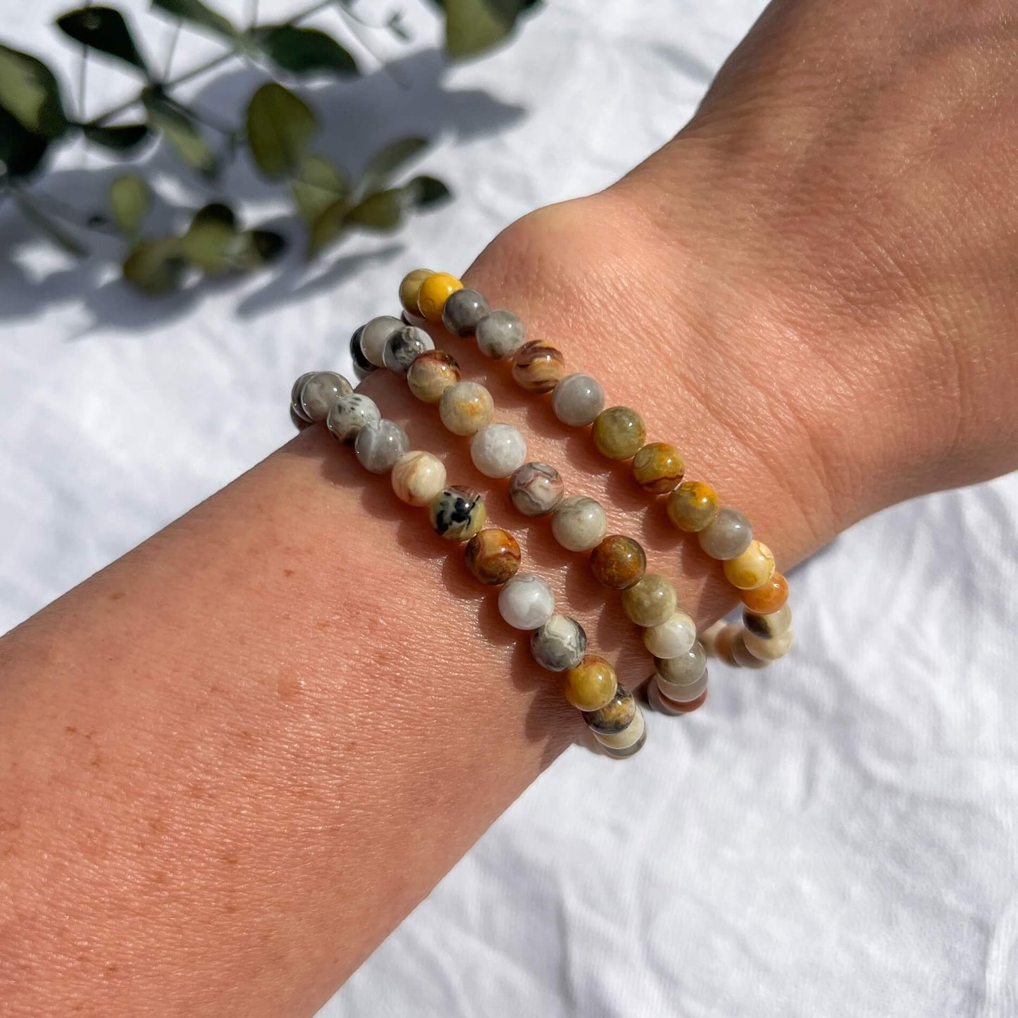 A woman's arm with 3 yellow, white & amber coloured crazy lace agate crystal bead bracelets
