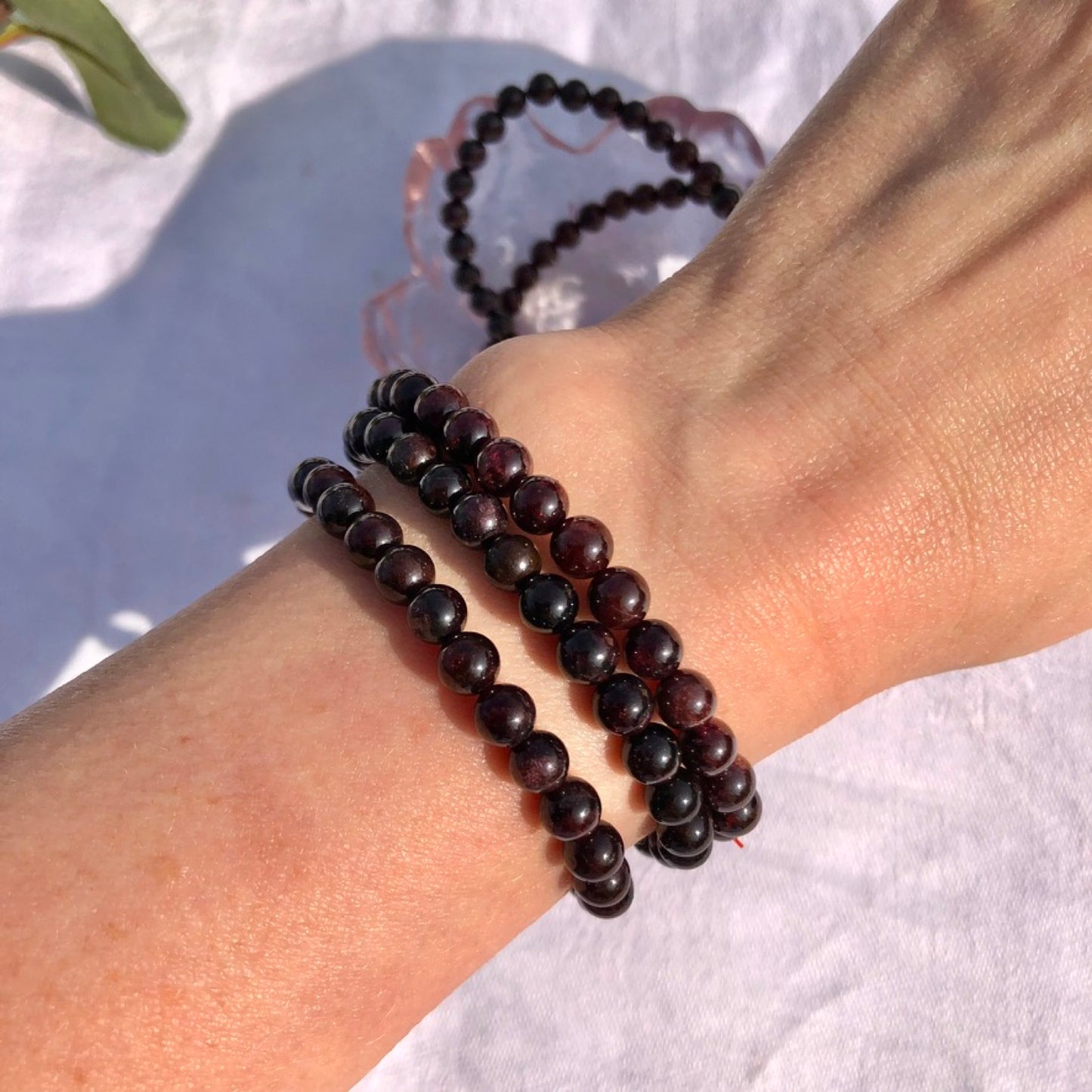 dark red garnet healing crystal bead bracelets worn on a slender wrist