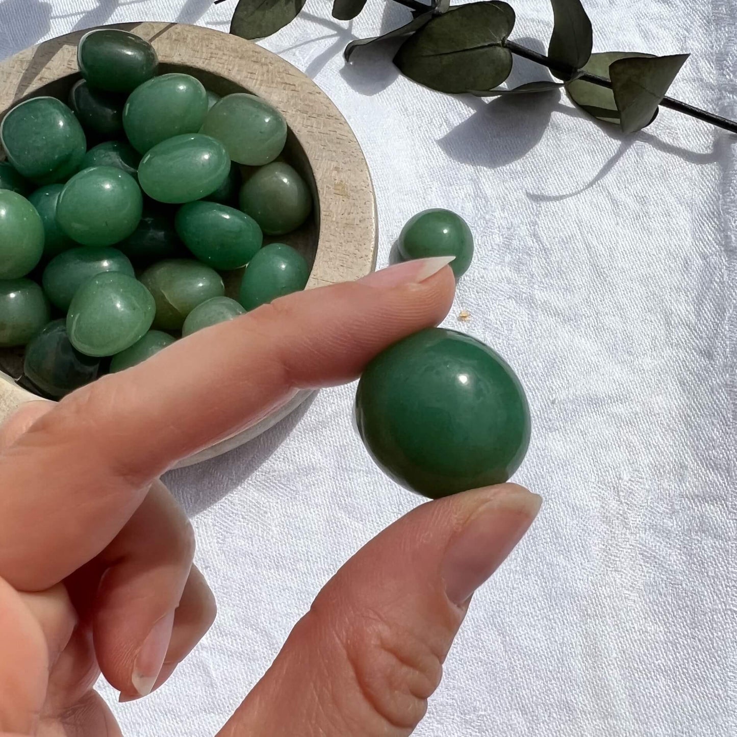 A perfect green glossy Green Aventurine crystal tumble stone held to camera