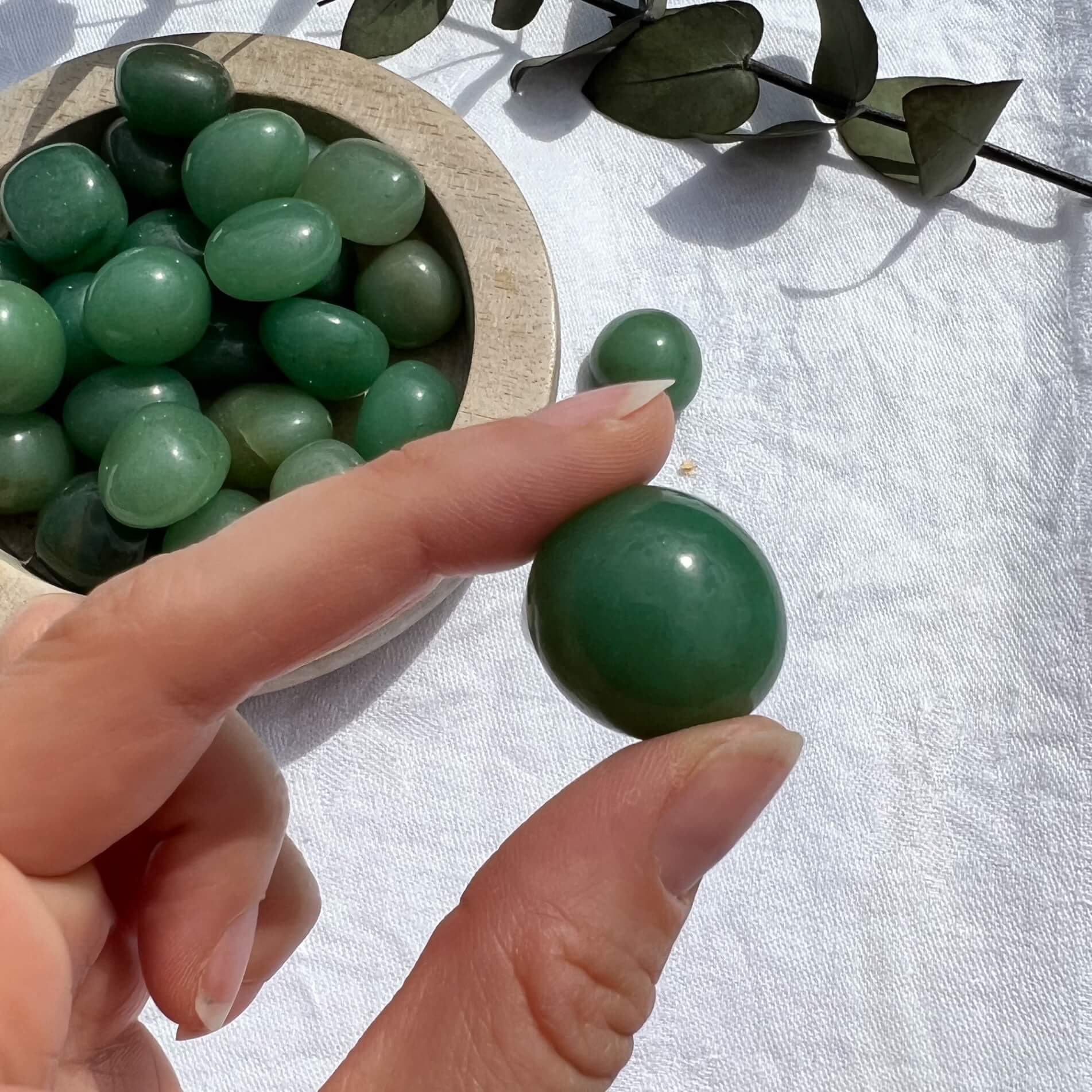 A perfect green glossy Green Aventurine crystal tumble stone held to camera