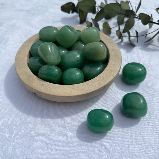 Juicy green aventurine crystal pebbles in a wooden dish with eucalyptus