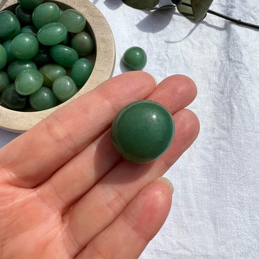 A perfect green glossy Green Aventurine crystal tumble stone in an outstretched hand