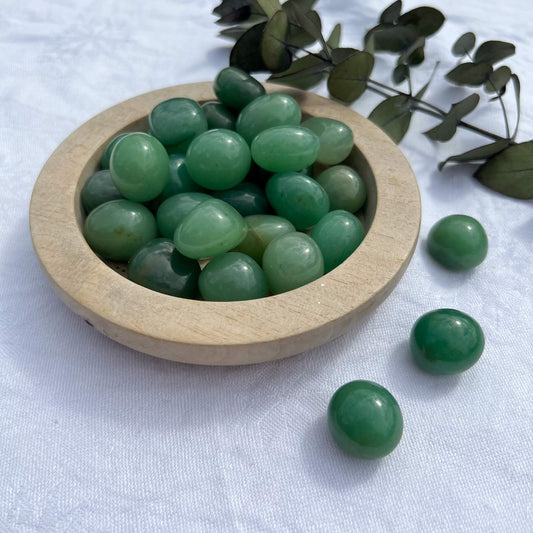 Beautiful bright and glossy Green Aventurine crystal tumblestones spilling from a wooden dish
