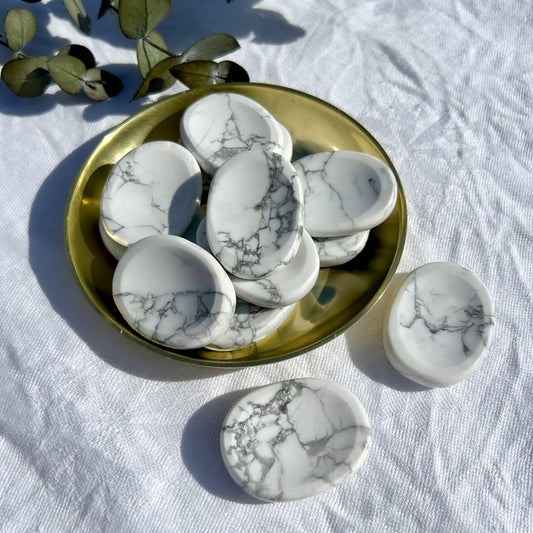 White and grey marbled howlite crystal worry stones in a brass dish