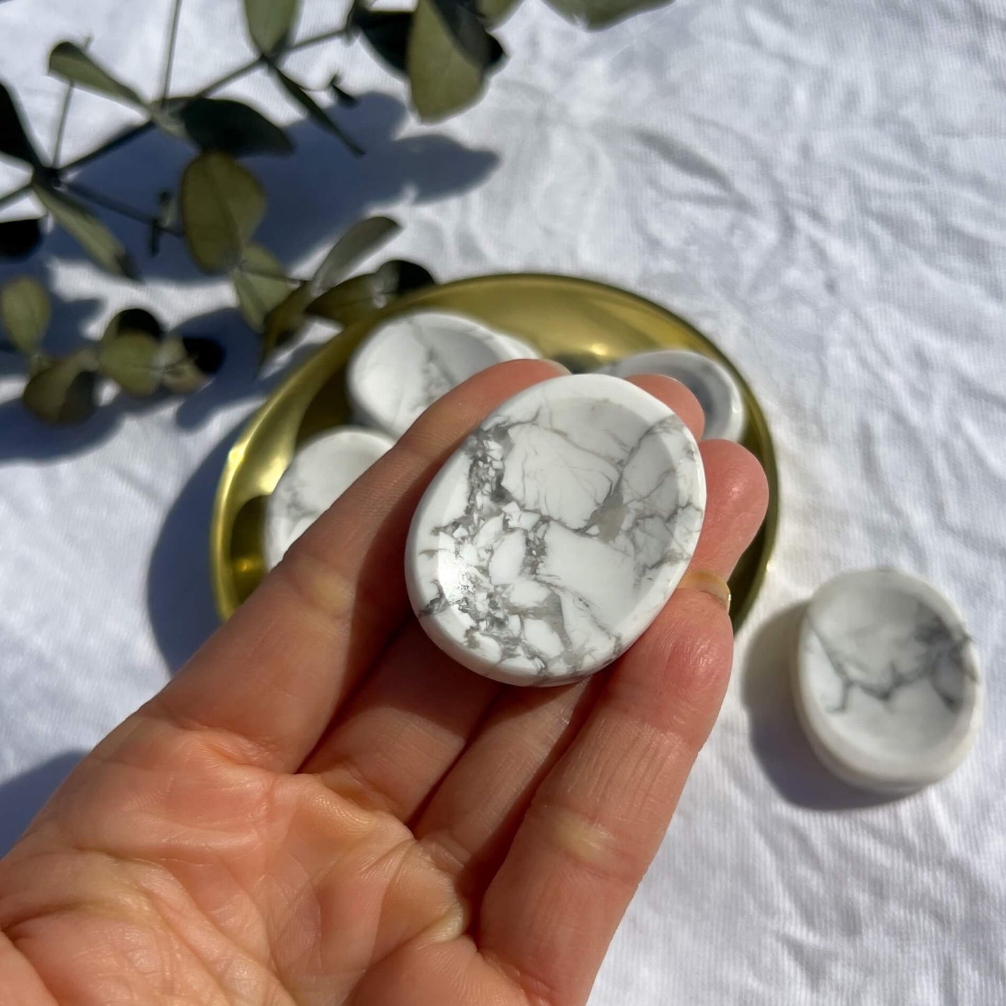White and grey marbled howlite crystal worrystone held in an open hand