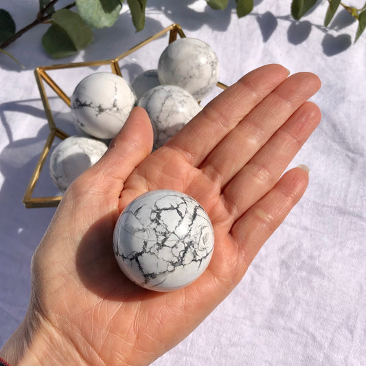 White and grey Howlite crystal sphere held in an open palm