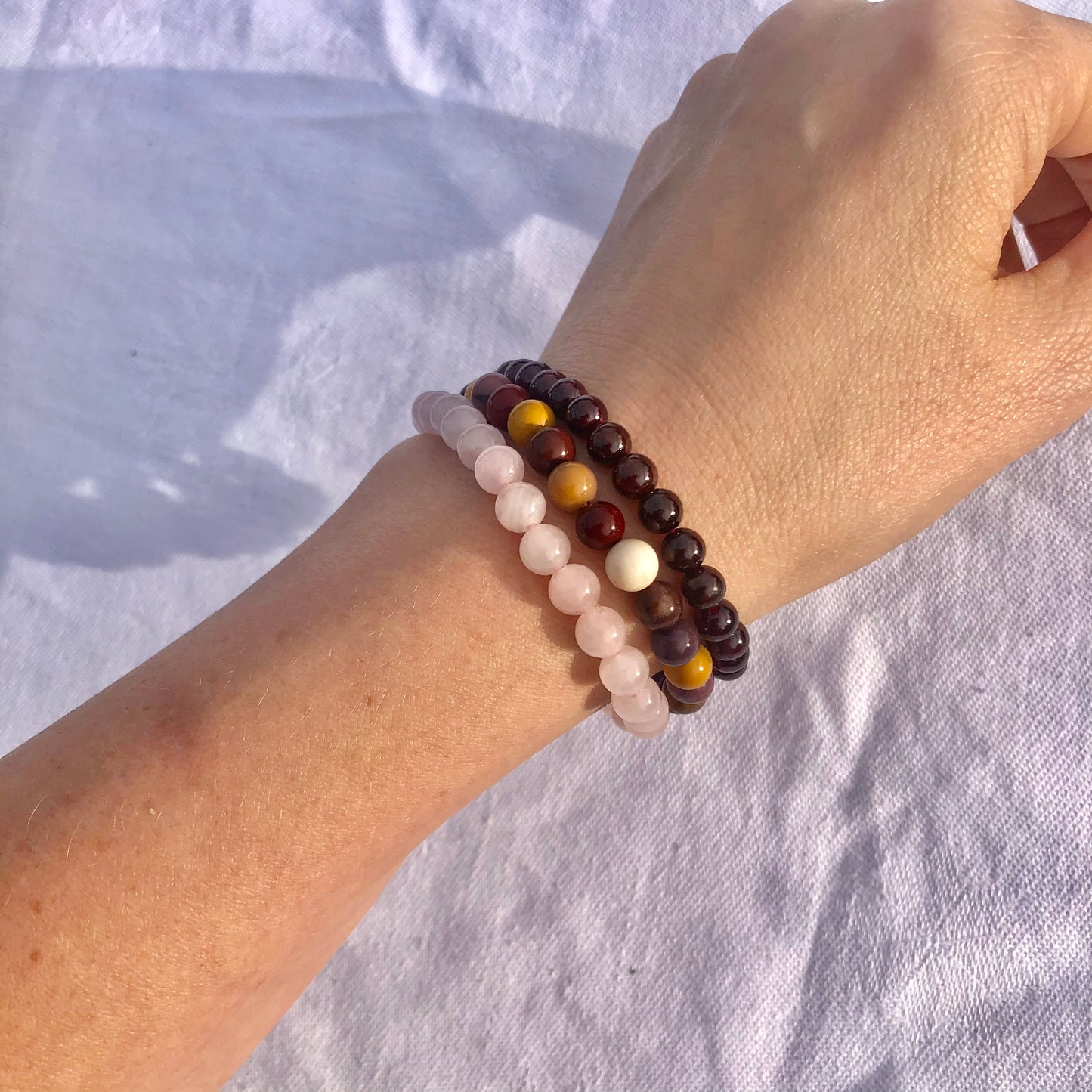 pink rose quartz, dark red garnet and yellow and red Mookaite crystal bead bracelets worn together