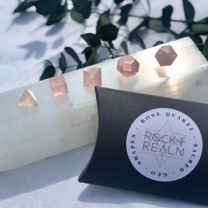 Rose Quartz Sacred Geometry shapes lined up on a glistening selenite log in the sun