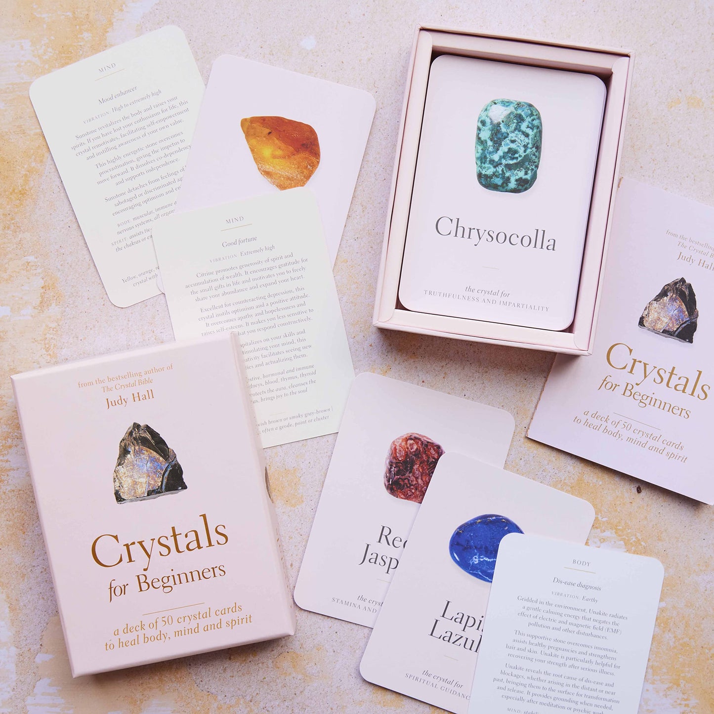 An open box of Crystals for Beginners cards showing a spread of pale pink cards with crystals and text on them