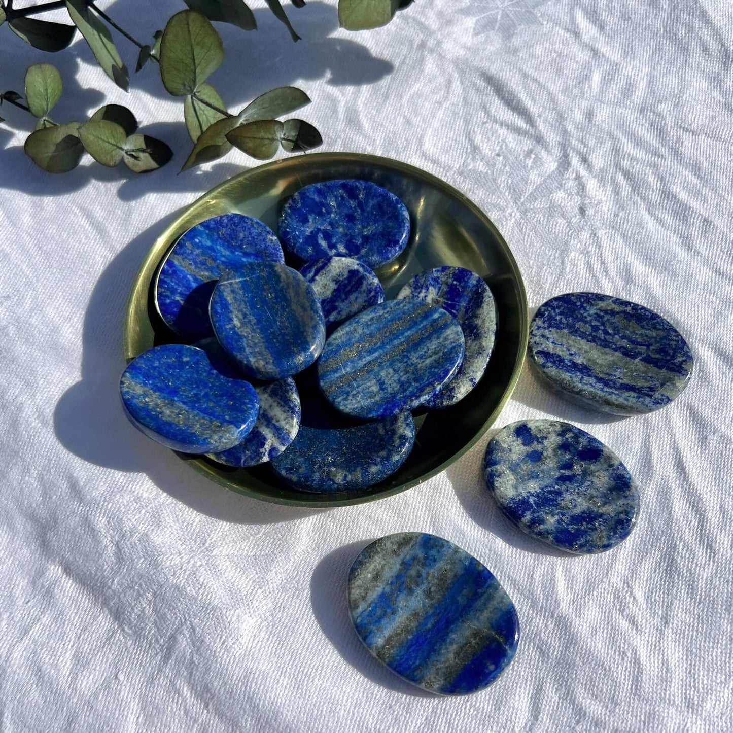 Royal blue, white and gold round Lapis Lazuli crystal thumb stones displayed in a brass dish