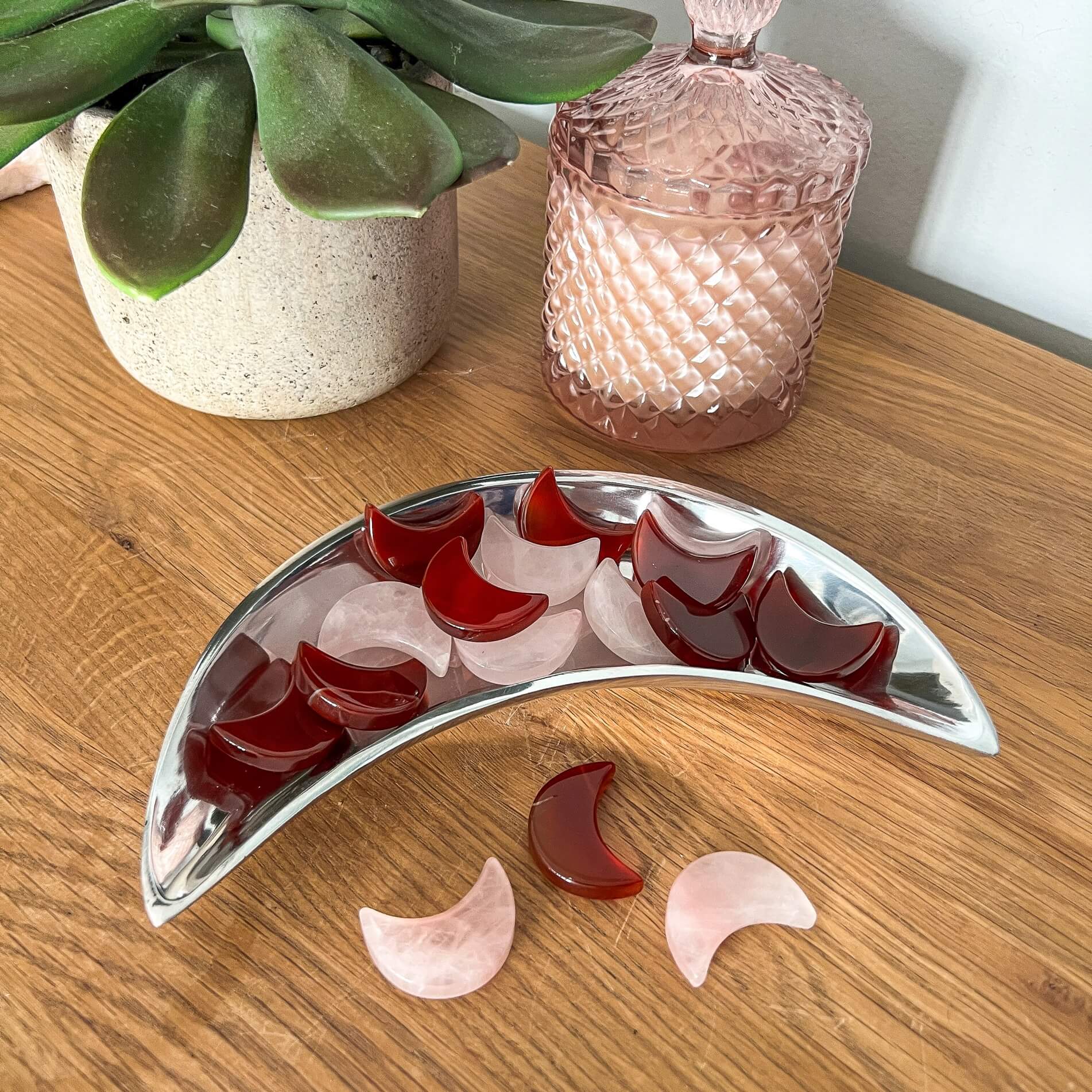 A silver moon dish filled with red carnelian crystal and pink rose quartz crystal moon decorations