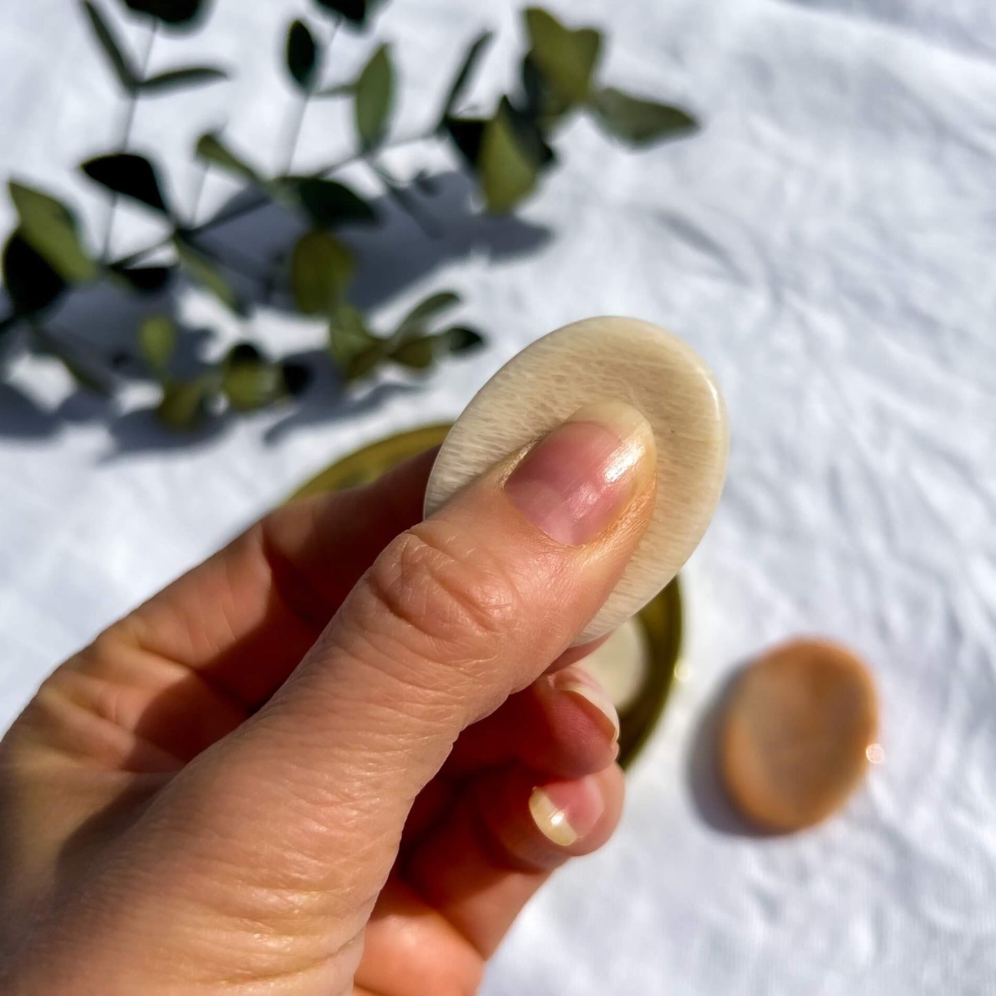 Peach moonstone disc shaped crystal worry stone rubbed between thumb and fingers