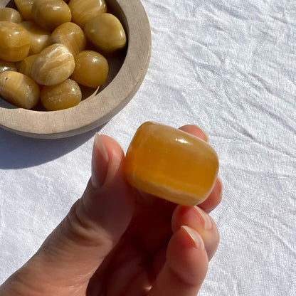 A glossy and juicy looking orange calcite crystal pebble