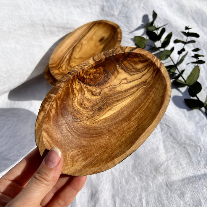 Two Warm honey coloured olive wooden bowl held to camera